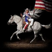 La pop star Beyoncé portant une tenue de cow-boy rouge, blanche et bleue, assise à l'envers sur un cheval blanc, avec un drapeau américain